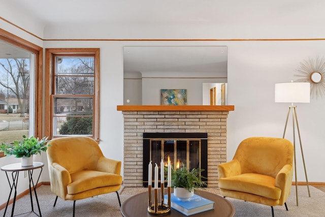 living area featuring carpet, a brick fireplace, and a healthy amount of sunlight