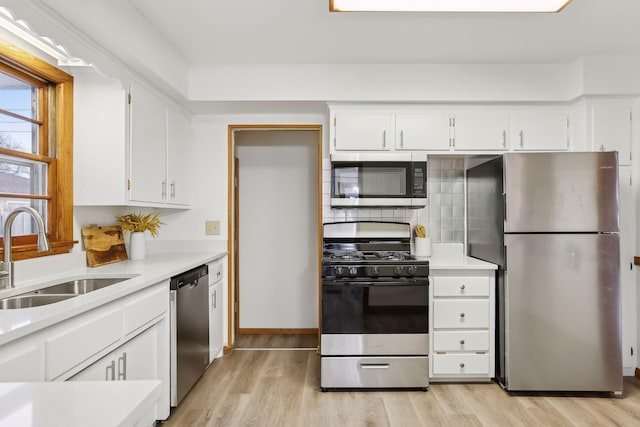 kitchen featuring backsplash, stainless steel appliances, sink, light hardwood / wood-style floors, and white cabinetry