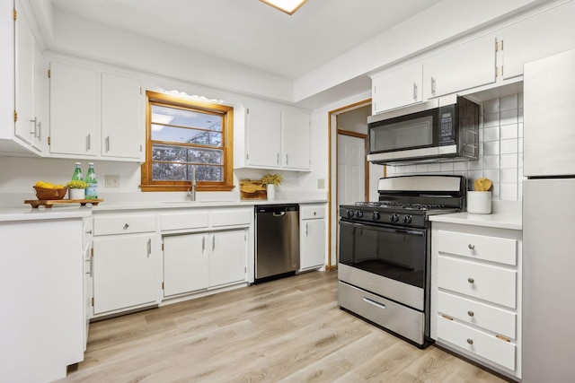 kitchen with white cabinets, stainless steel appliances, light hardwood / wood-style floors, and sink