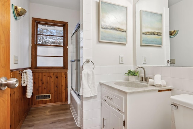 full bathroom with toilet, shower / bath combination with glass door, vanity, tile walls, and hardwood / wood-style flooring