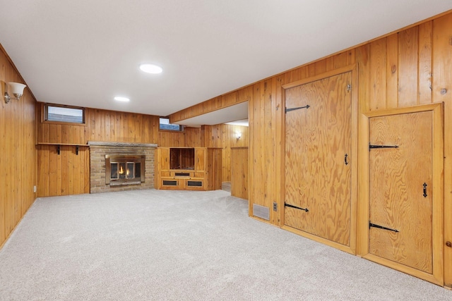 basement featuring wood walls, light colored carpet, and a fireplace