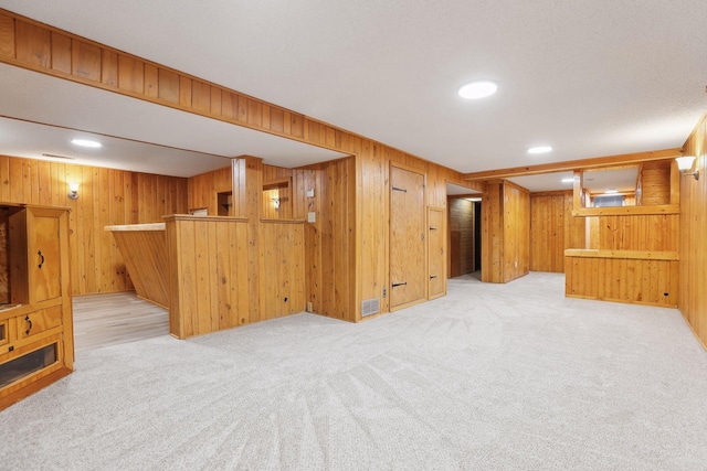 interior space with light carpet and wooden walls