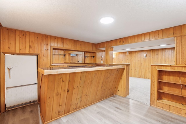 kitchen featuring kitchen peninsula, wooden walls, and light hardwood / wood-style floors