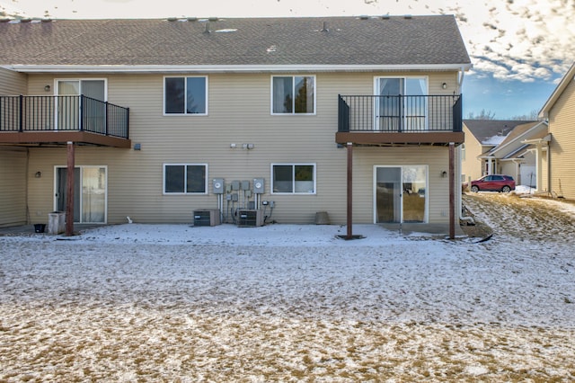 snow covered back of property with a balcony and cooling unit