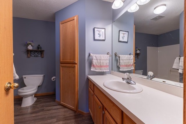 bathroom with hardwood / wood-style floors, vanity, a textured ceiling, toilet, and walk in shower