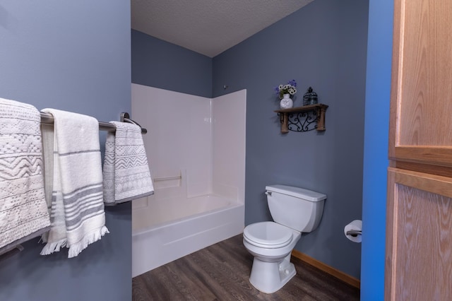 bathroom with bathtub / shower combination, hardwood / wood-style floors, a textured ceiling, and toilet