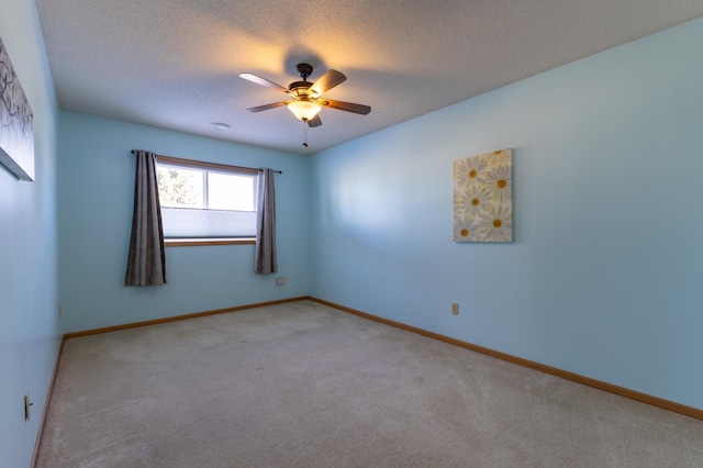 spare room featuring ceiling fan, light colored carpet, and a textured ceiling