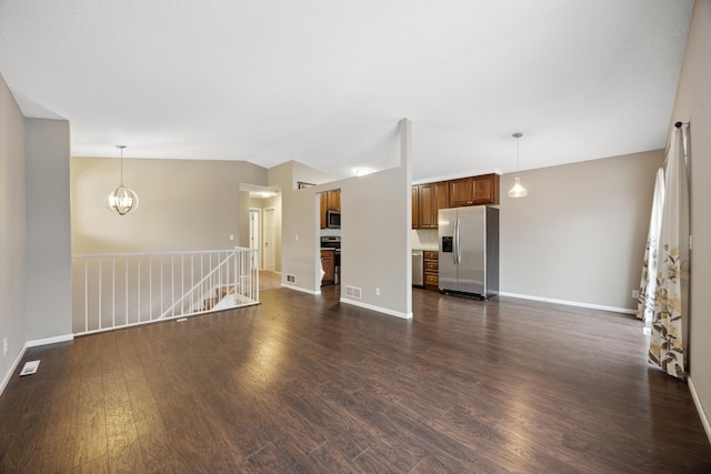 unfurnished living room with dark hardwood / wood-style floors, vaulted ceiling, and a notable chandelier