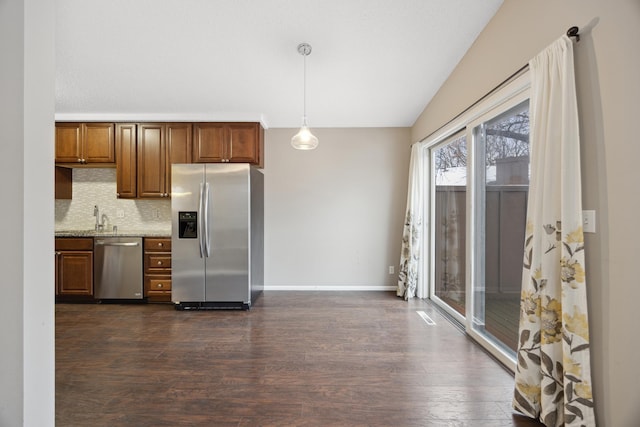 kitchen with light stone counters, appliances with stainless steel finishes, dark hardwood / wood-style floors, pendant lighting, and decorative backsplash