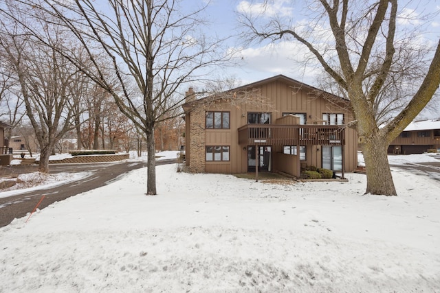 snow covered back of property featuring a deck