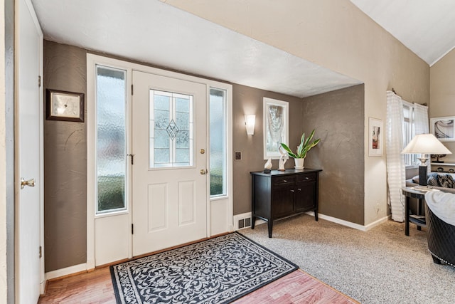 carpeted foyer with lofted ceiling