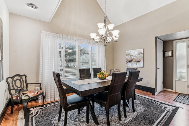 dining room with wood-type flooring, lofted ceiling, and a notable chandelier