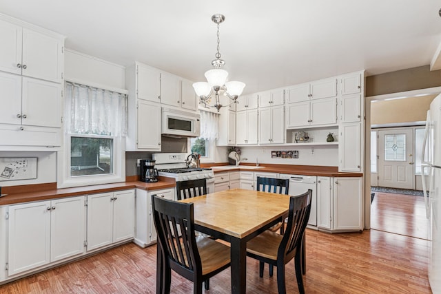 kitchen featuring white cabinetry, pendant lighting, and white appliances