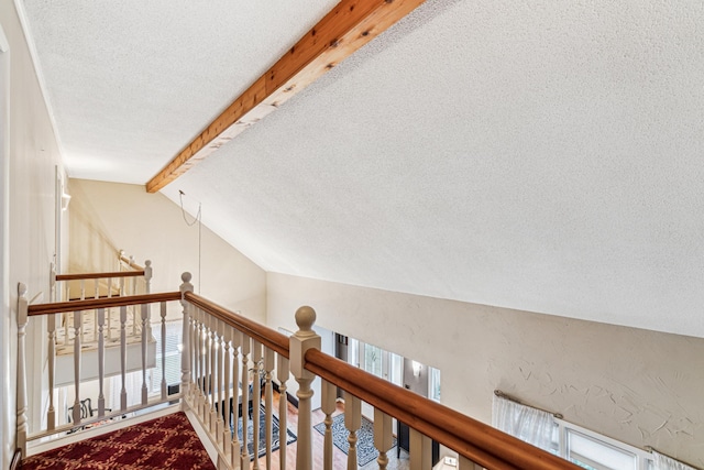 corridor featuring carpet floors, lofted ceiling with beams, and a textured ceiling