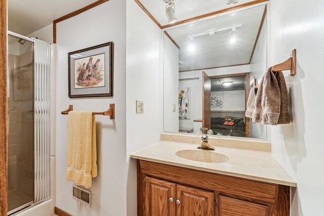 bathroom featuring a shower with door, vanity, and rail lighting