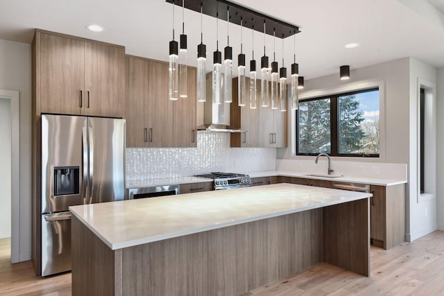 kitchen featuring wall chimney exhaust hood, appliances with stainless steel finishes, sink, and a kitchen island