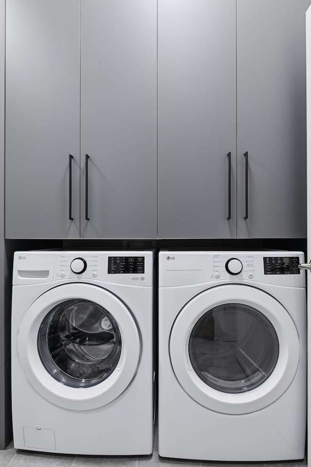 clothes washing area featuring cabinets and washer and clothes dryer