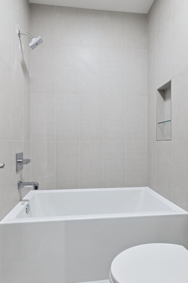 bathroom with tiled shower / bath combo and toilet