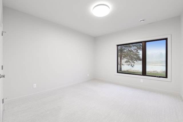 unfurnished room featuring baseboards and light carpet