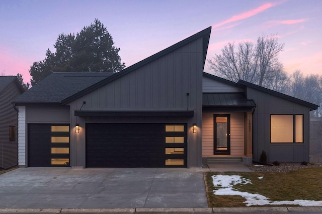 contemporary house featuring an attached garage, concrete driveway, and a standing seam roof