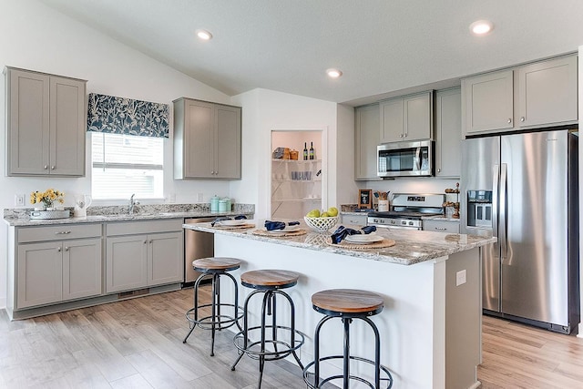 kitchen featuring a breakfast bar, a kitchen island, vaulted ceiling, and appliances with stainless steel finishes