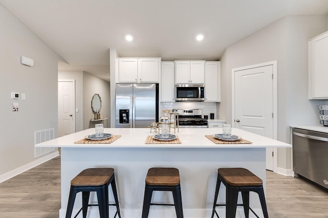 kitchen with white cabinetry, a breakfast bar, a kitchen island, and appliances with stainless steel finishes