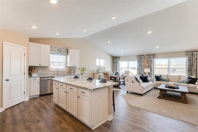 kitchen with sink, stainless steel dishwasher, a textured ceiling, a kitchen island, and white cabinetry