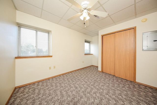 unfurnished bedroom featuring a paneled ceiling, ceiling fan, a closet, and carpet floors