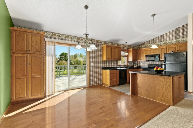 kitchen featuring a notable chandelier, decorative light fixtures, a kitchen island, black appliances, and light wood-type flooring