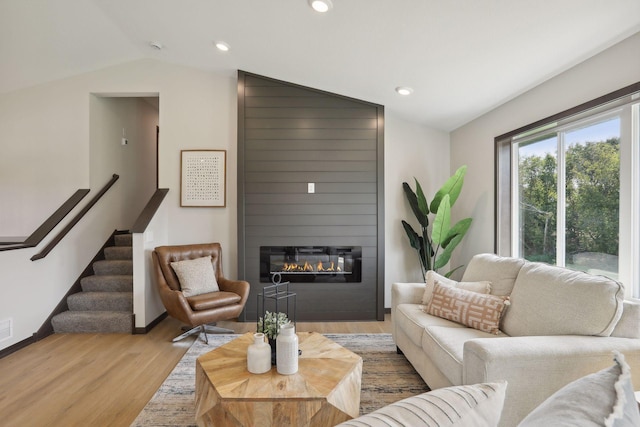 living room featuring a fireplace, light hardwood / wood-style floors, and vaulted ceiling