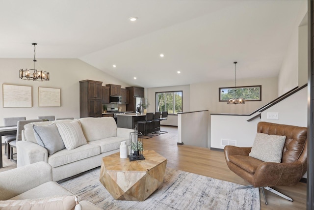 living room with light wood-type flooring, vaulted ceiling, and a notable chandelier