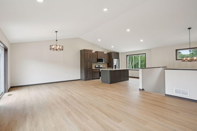 kitchen with stainless steel appliances, a center island, pendant lighting, and a notable chandelier