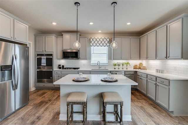 kitchen featuring decorative light fixtures, appliances with stainless steel finishes, sink, and a kitchen island