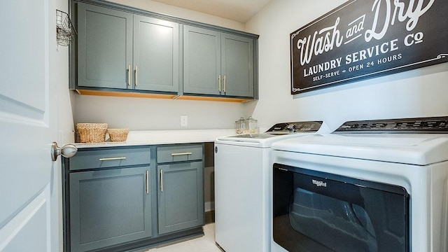 clothes washing area with cabinets and washer and clothes dryer