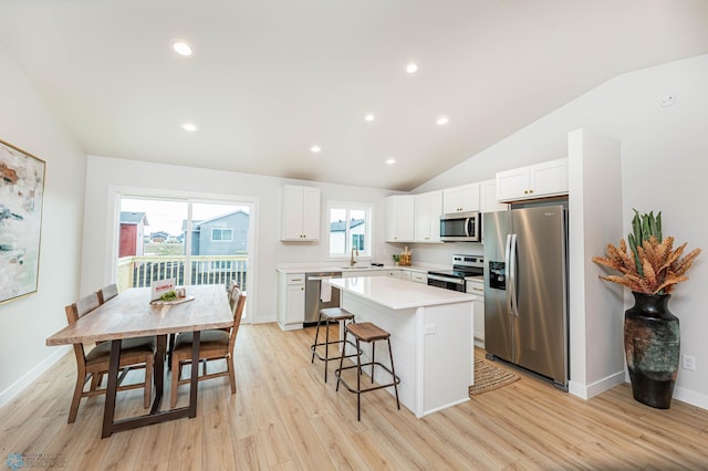 kitchen with white cabinets, a kitchen island, light wood-type flooring, and appliances with stainless steel finishes