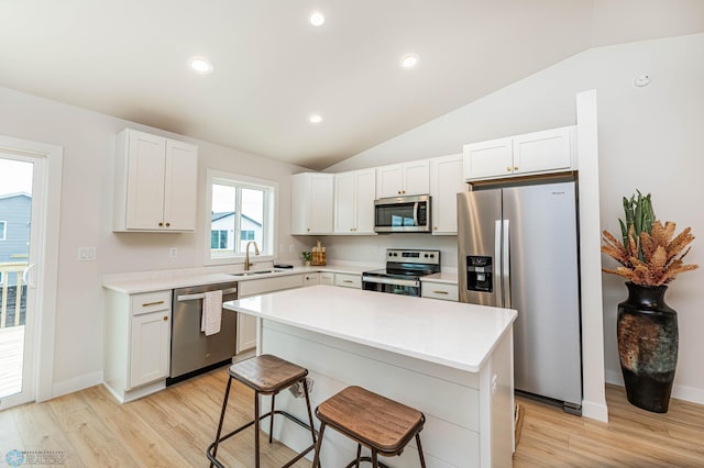 kitchen featuring a breakfast bar, white cabinets, light hardwood / wood-style flooring, a kitchen island, and stainless steel appliances