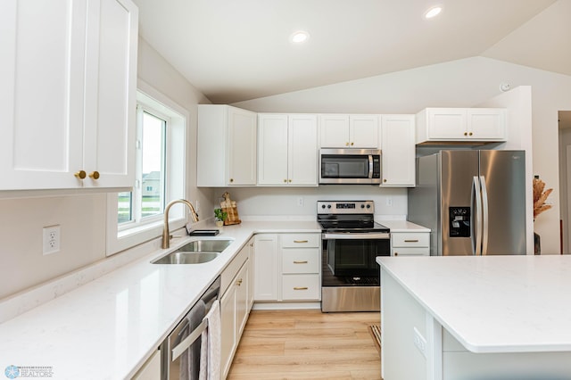 kitchen featuring white cabinetry, sink, vaulted ceiling, and appliances with stainless steel finishes