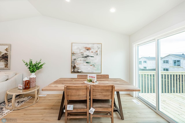 dining room featuring light wood-type flooring and vaulted ceiling