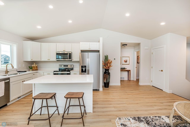 kitchen featuring a center island, sink, light wood-type flooring, white cabinetry, and stainless steel appliances