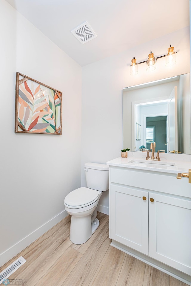 bathroom with toilet, vanity, and hardwood / wood-style flooring