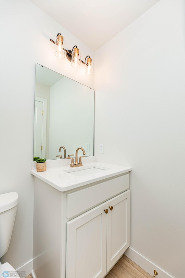 bathroom with hardwood / wood-style flooring, vanity, and toilet