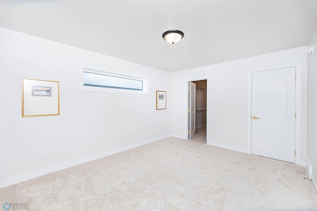 unfurnished bedroom with light carpet, a spacious closet, and a closet