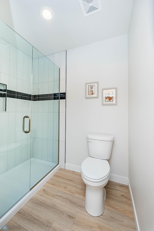 bathroom featuring hardwood / wood-style flooring, toilet, and a shower with shower door