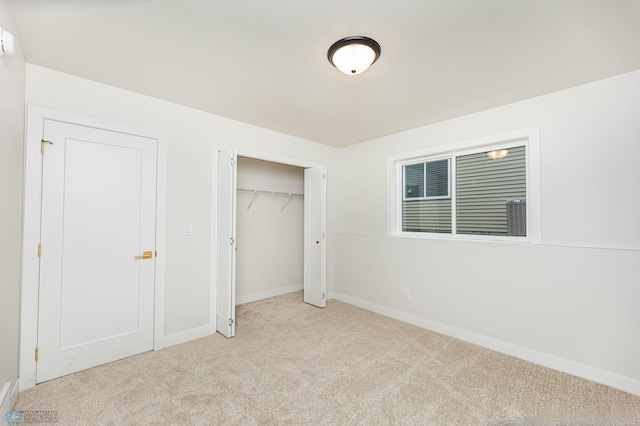 unfurnished bedroom with light colored carpet and a closet