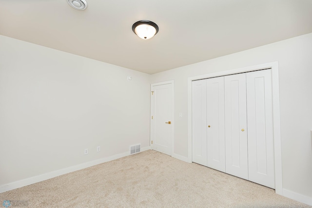 unfurnished bedroom with light carpet and a closet