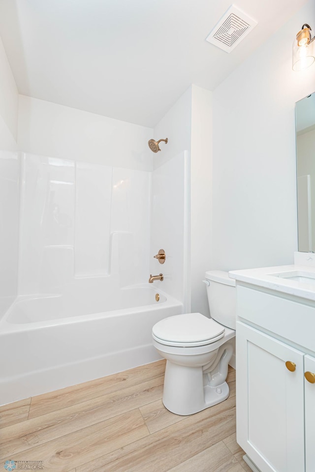 full bathroom featuring toilet, vanity, hardwood / wood-style flooring, and bathing tub / shower combination