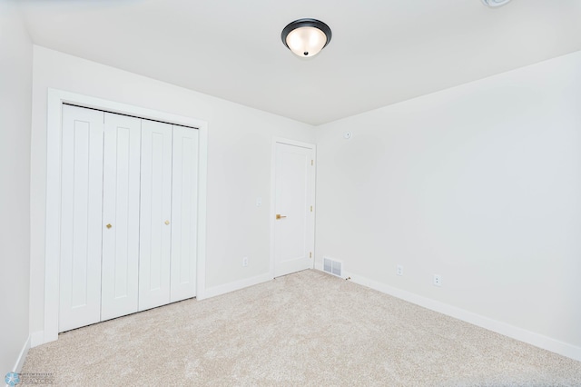 unfurnished bedroom featuring light carpet and a closet