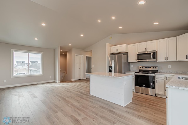 kitchen with white cabinetry, light hardwood / wood-style floors, vaulted ceiling, a kitchen island, and appliances with stainless steel finishes