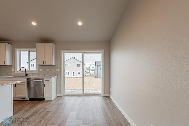 kitchen featuring white cabinets, light hardwood / wood-style floors, stainless steel dishwasher, and plenty of natural light