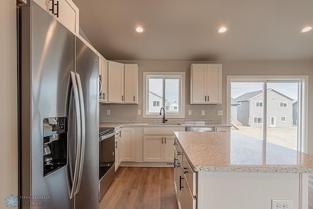 kitchen featuring light stone counters, sink, white cabinetry, and stainless steel appliances